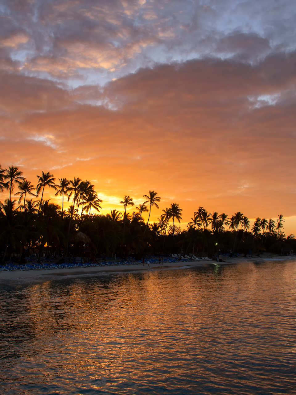 Ein weiter Strand mit Palmen bei Sonnenuntergang